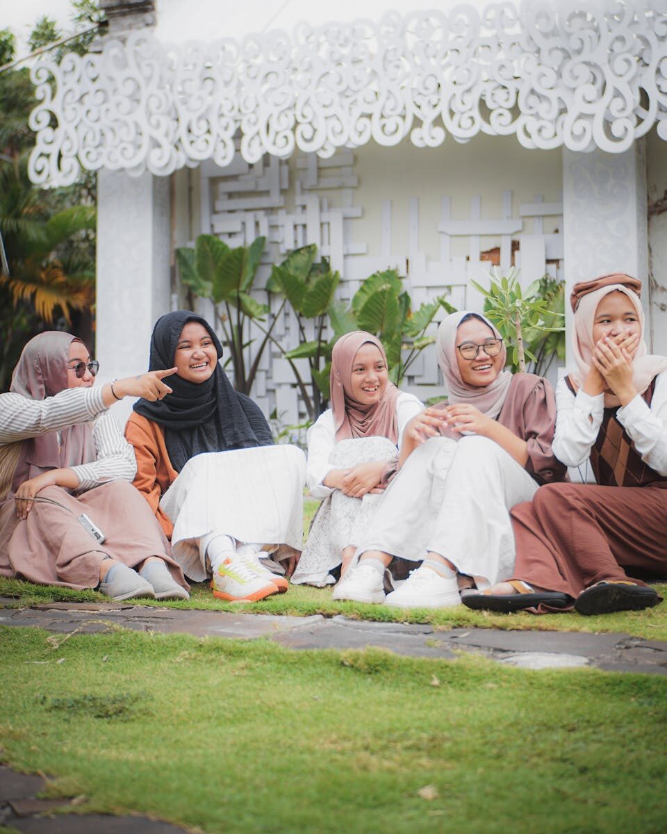 Young women in Surakarta, Indonesia, laughing and bonding outdoors in a refreshing setting.